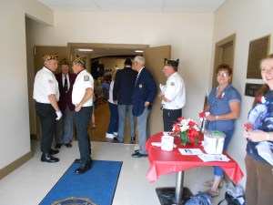 Entering the building, we have our greeters, American Legion members getting ready for the ceremony, and the poppy table to pick up your poppies.